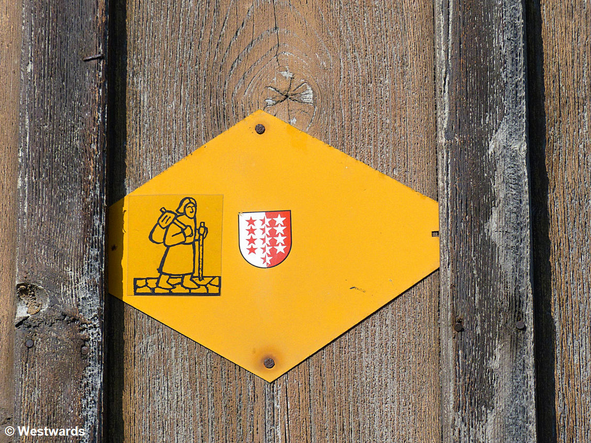 hiking sign with pilgrim and valais coat of arms