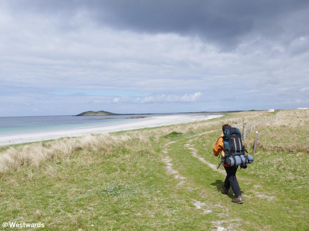 Woman hiking the Hebridean Way along the white beach in South Uist