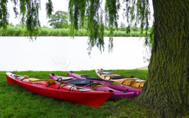 Four colorful kayaks lying on the gras