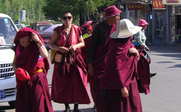 Monks and nuns with red robes and sun glasses and sunhats in Wutaishan