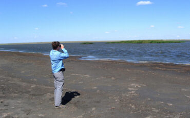 Isa with binoculars on the shore of Lake Sumai