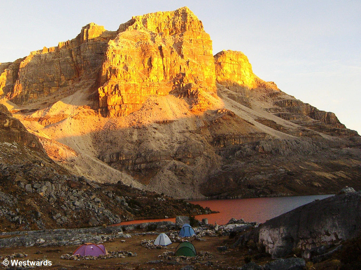 4 tents of hikers with El Cocuy's Laguna de la Plaza and mountain, both red from sunset