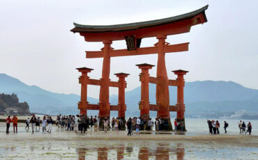 Shrine gate of Miyajima at low tide with tourists walking around