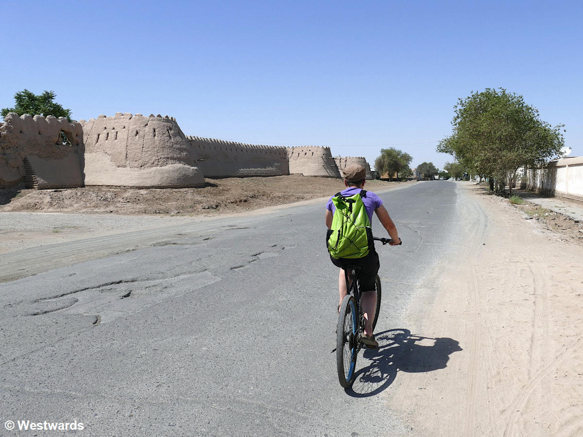 travel blogger cycling in unusual streets in Khiva, along the outer city wall